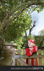 Portrait of young boy (7-9) wearing pirate costume leaning on garden gate