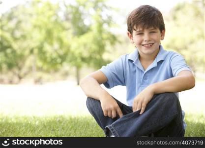 Portrait Of Young Boy Sitting In Park