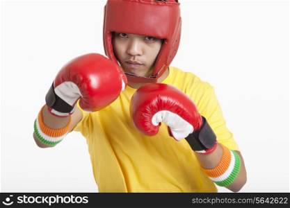 Portrait of young boy wearing boxing gloves and head protector ready for the match over white background