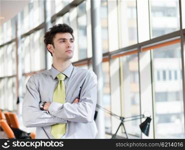 portrait of young business man at modern office interior with big windows in background