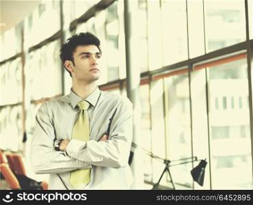 portrait of young business man at modern office interior with big windows in background