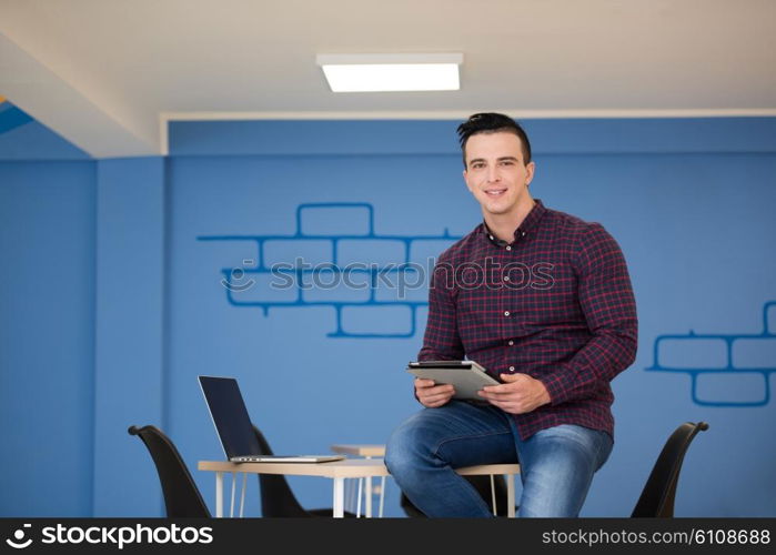 portrait of young business man in casual clothes sitting on table at new startup office space