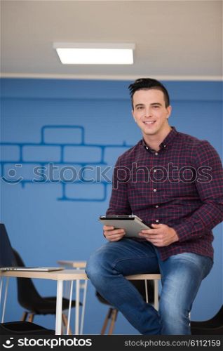 portrait of young business man in casual clothes sitting on table at new startup office space