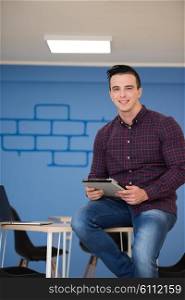 portrait of young business man in casual clothes sitting on table at new startup office space