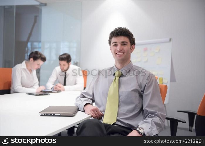 portrait of young business man with curly hair and at modern bright office interior with big windows in background
