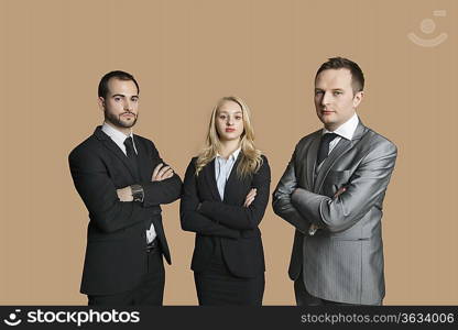 Portrait of young business people with arms crossed over colored background