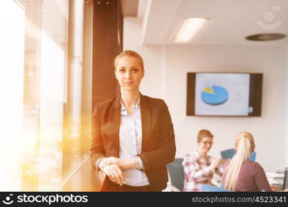 portrait of young business woman at modern startup office interior team in meeting group in background