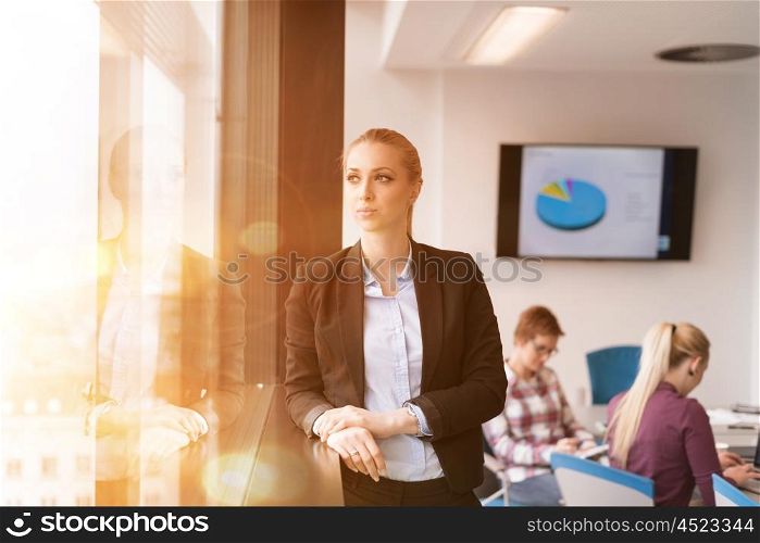 portrait of young business woman at modern startup office interior team in meeting group in background