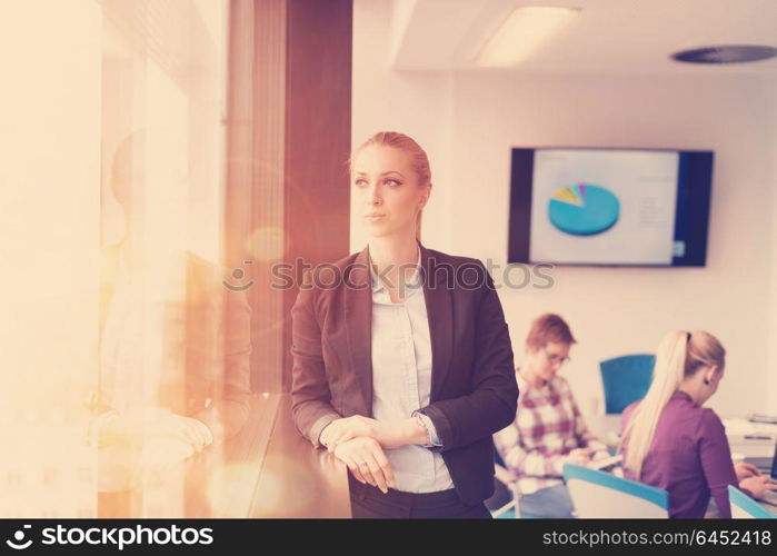 portrait of young business woman at modern startup office interior team in meeting group in background