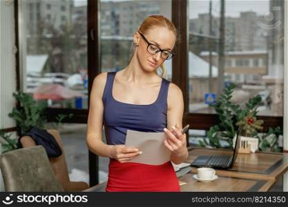 Portrait of young business woman holding and reading the documents in office.. Young business woman with documents.
