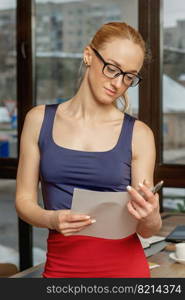 Portrait of young business woman holding and reading the documents in office.. Young business woman with documents.