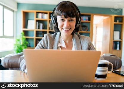 Portrait of young business woman on video call with laptop and headphones. Home office concept. New normal lifestyle.