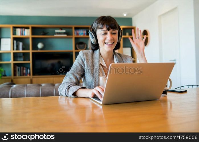 Portrait of young business woman on video call with laptop and headphones. Home office concept. New normal lifestyle.