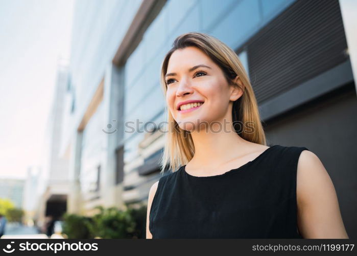 Portrait of young business woman standing outside office buildings. Business and success concept.