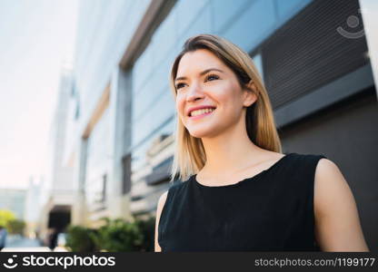 Portrait of young business woman standing outside office buildings. Business and success concept.