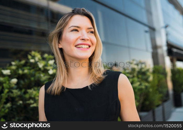 Portrait of young business woman standing outside office buildings. Business and success concept.