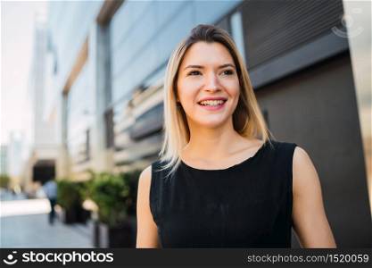 Portrait of young business woman standing outside office buildings. Business and success concept.