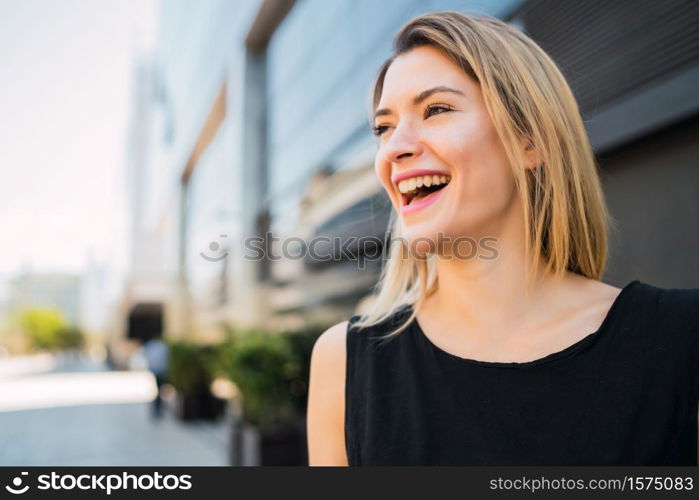 Portrait of young business woman standing outside office buildings. Business and success concept.