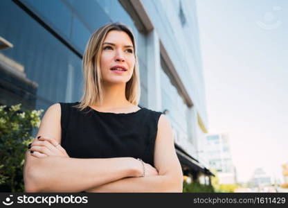 Portrait of young business woman standing outside office buildings. Business and success concept.