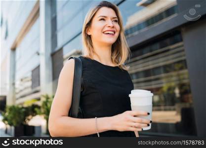 Portrait of young business woman walking to work while drinking takeaway coffee. Business and success concept.