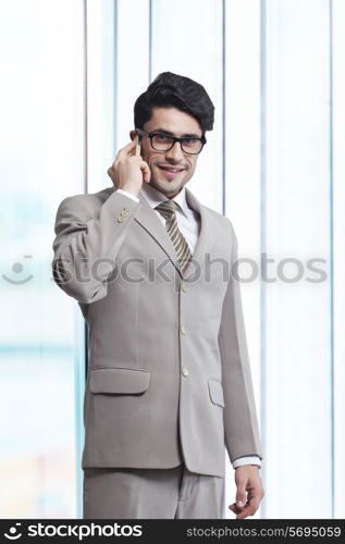 Portrait of young businessman answering smart phone in office