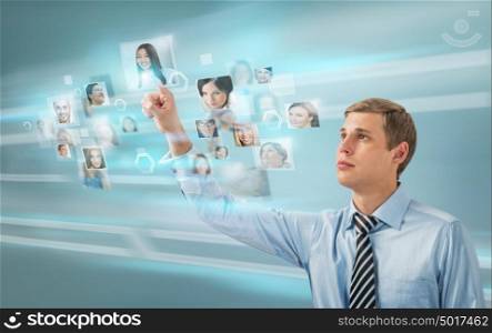 Portrait of young businessman choosing people for his business team using virtual computer interface