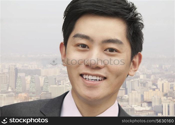 Portrait of young businessman close-up, cityscape in background