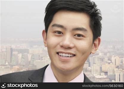 Portrait of young businessman close-up, cityscape in background