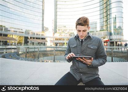 Portrait of young businessman commuter using digital tablet.