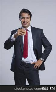 Portrait of young businessman drinking tea over gray background