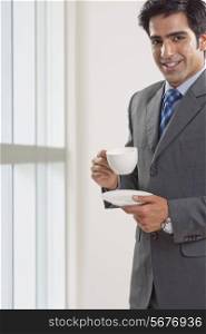 Portrait of young businessman having coffee cup in office