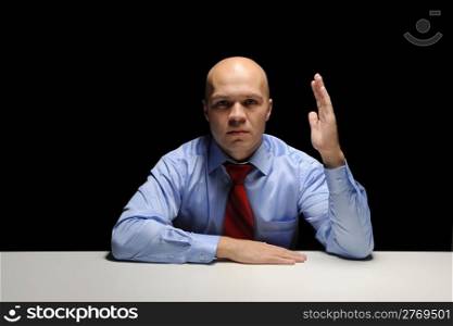 Portrait of young businessman holding hand up in a dark room