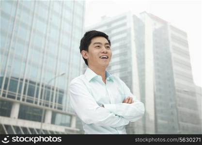 Portrait of young businessman in button down shirt with arms crossed, outdoors, Beijing