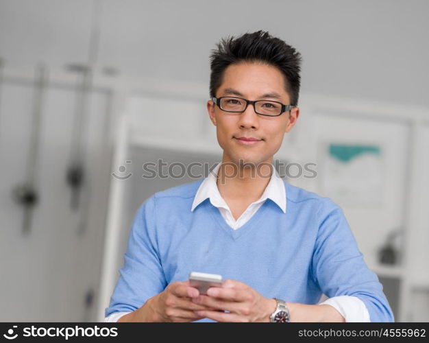 Portrait of young businessman in office holding his mobile. Portrait of young businessman with mobile