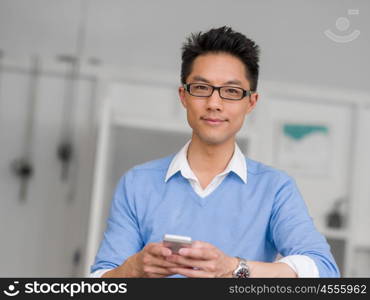 Portrait of young businessman in office holding his mobile. Portrait of young businessman with mobile