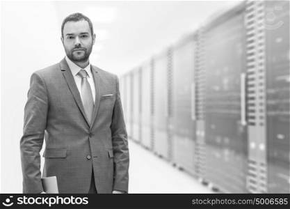 Portrait of young businessman in server room using tablet