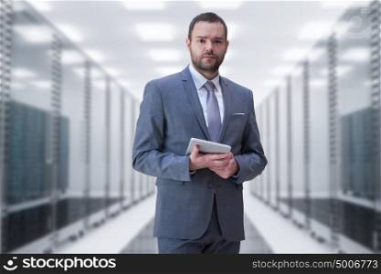 Portrait of young businessman in server room using tablet