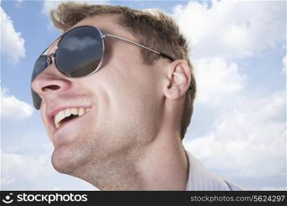 Portrait of young businessman in sunglasses smiling, close-up on face