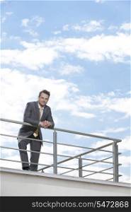 Portrait of young businessman leaning on terrace railings