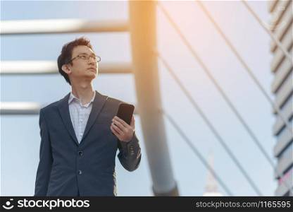 Portrait of young businessman outdoor. Businessman using smart phone for dealing business.