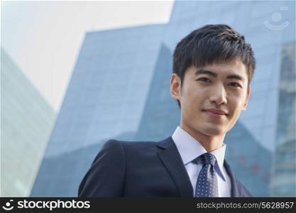 Portrait of young businessman outside glass building