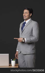 Portrait of young businessman pointing sideways in office