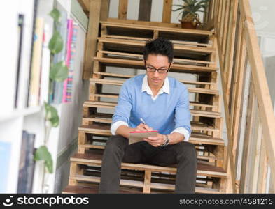 Portrait of young businessman sitting at the stairs in office. Portrait of young businessman in casual