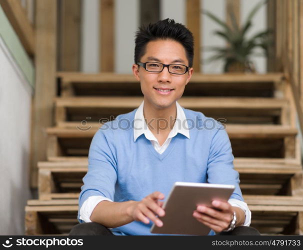 Portrait of young businessman sitting at the stairs in office. Portrait of young businessman in casual