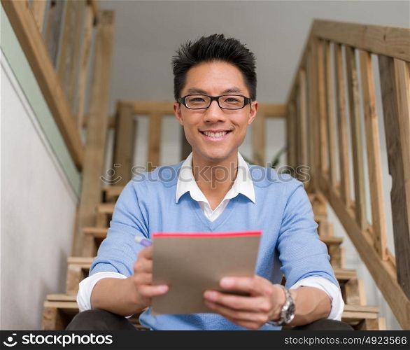 Portrait of young businessman sitting at the stairs in office. Portrait of young businessman in casual