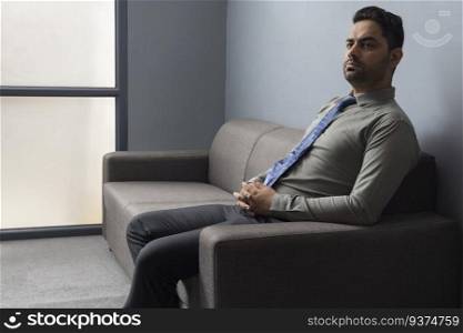 Portrait of young businessman sitting on sofa in office