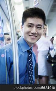 Portrait of young businessman sitting on the subway and looking at the camera