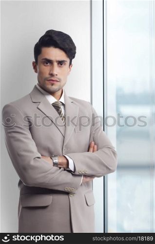 Portrait of young businessman standing arms crossed in office