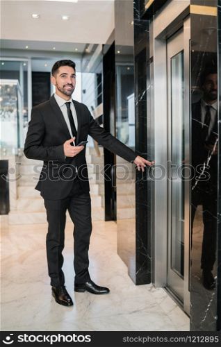 Portrait of young businessman standing at hotel lobby. Business trip and travel concept.