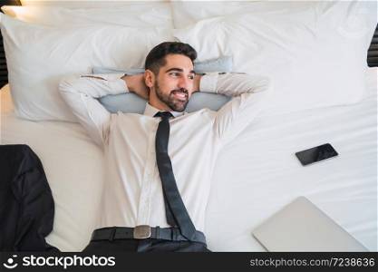 Portrait of young businessman taking a break from work and relaxing after a hard day at the hotel room. Business travel concept.
